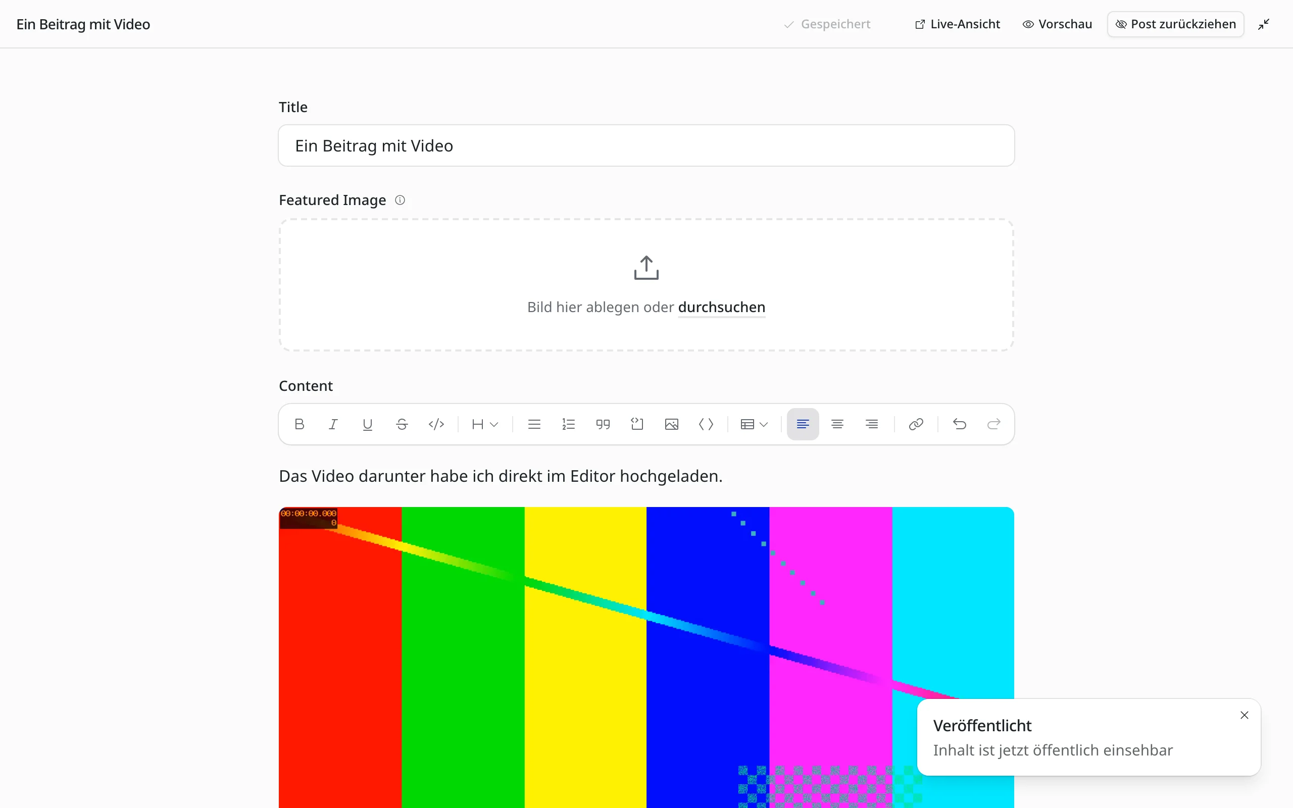 Der EmDash-Editor im ablenkungsfreien Modus. Oben eine schmale Leiste mit dem Titel „Ein Beitrag mit Video“, dem Status Gespeichert und den Knöpfen Live-Ansicht, Vorschau und Post zurückziehen. Darunter zentriert Titel, Featured Image und der Text mit einem eingebetteten Video. Unten rechts die Meldung „Veröffentlicht“.